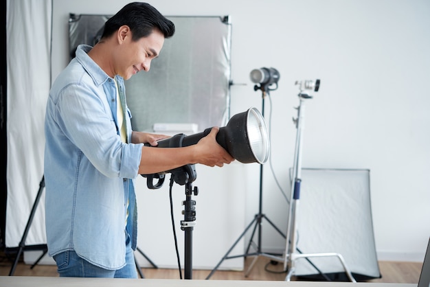 Fotógrafo asiático instalando iluminación en estudio profesional