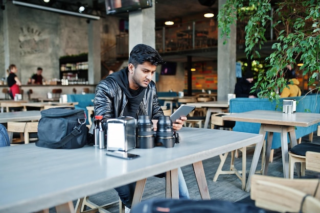 Foto gratuita fotógrafo inteligente joven asiático trabajando con tableta durante sentado en el café