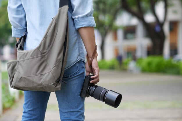 Fotógrafo irreconocible de pie en el parque y sosteniendo la cámara