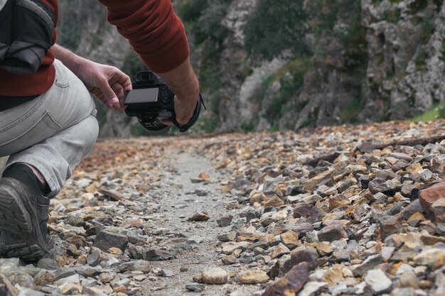 Fotógrafo joven que toma una foto con una cámara en un camino de piedra, anteriormente una vía de tren.