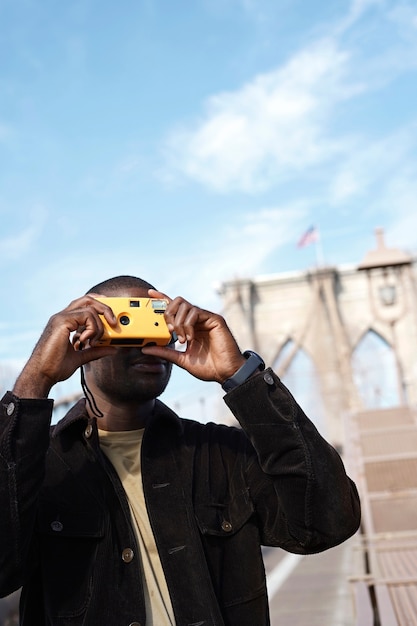 Fotógrafo masculino con estilo joven con cámara mientras explora la ciudad