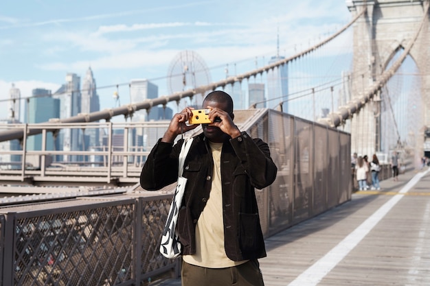 Fotógrafo masculino con estilo joven con cámara mientras explora la ciudad