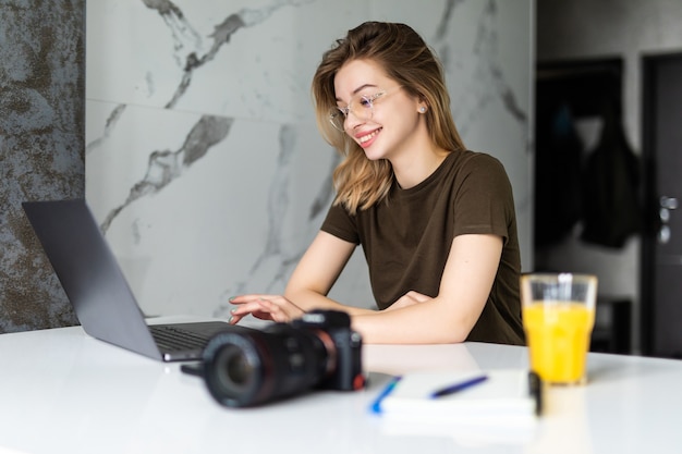 Fotógrafo de mujer bonita joven que trabaja desde casa en la computadora portátil