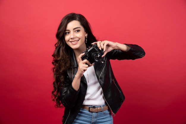 Fotógrafo de mujer hermosa con cámara de fotos sobre un fondo rojo. Foto de alta calidad