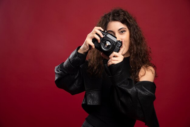 Fotógrafo de mujer en traje negro tomando fotografías con una cámara.