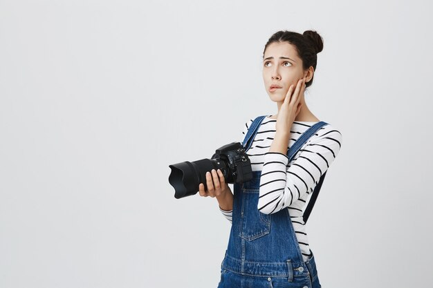 Fotógrafo de niña preocupada que se siente nerviosa. Mujer sosteniendo la cámara y se siente molesto