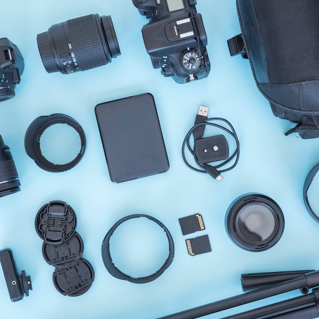 Fotógrafo profesional de accesorios y equipos dispuestos sobre fondo azul.