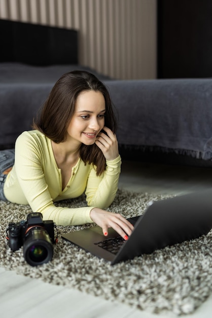 Fotógrafo de sexo femenino joven con la computadora portátil que usa la cámara de fotos dslr moderna.