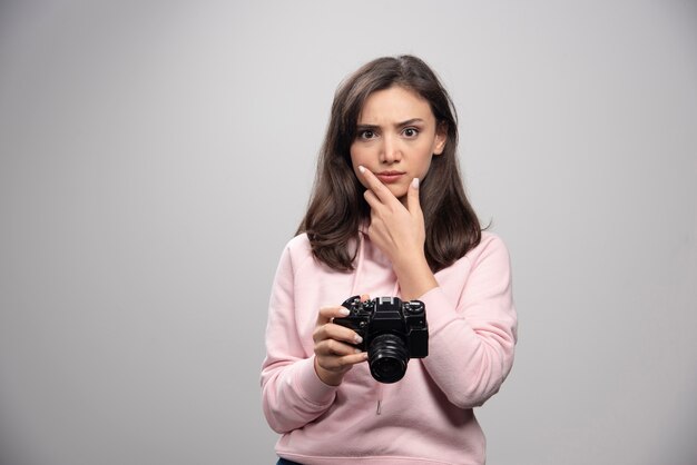 Fotógrafo de sexo femenino que sostiene la cámara y el pensamiento.