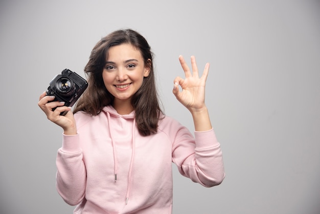 Fotógrafo de sexo femenino que sostiene la cámara y que hace la muestra aceptable.