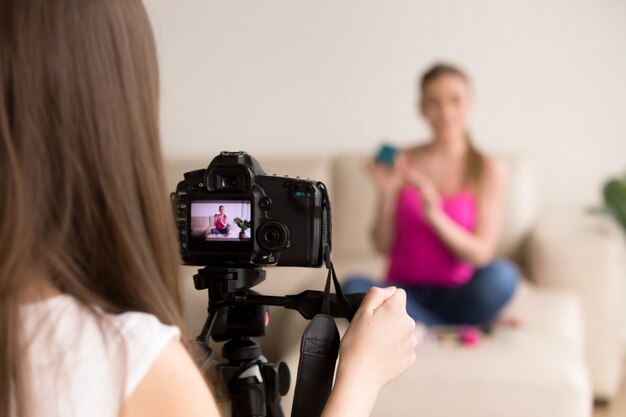 Fotógrafo de sexo femenino que toma la foto de la muchacha en el sofá.