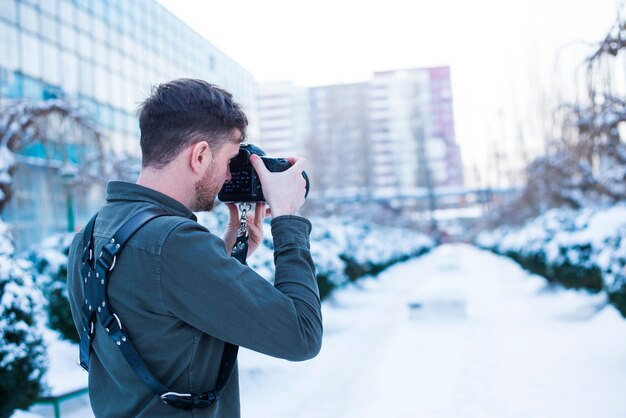 Fotógrafo de sexo masculino que toma la imagen de la calle nevosa