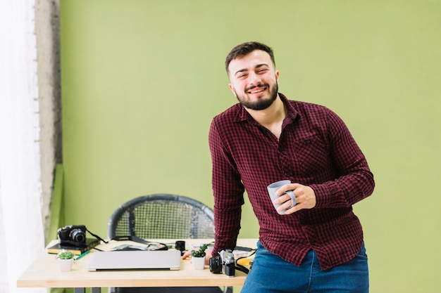 Foto gratuita fotógrafo sonriente bebiendo café