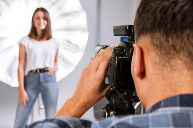 Fotógrafo tomando una foto de una mujer modelo en estudio