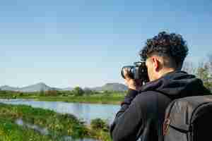 Foto gratuita fotógrafo viajero tomando foto con mochila.