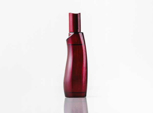 Una fragancia de botella de color rojo oscuro de vista frontal aislada en el escritorio blanco