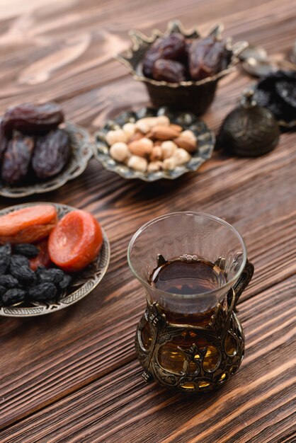 Fragante té turco con frutos secos; Nueces y fechas en el escritorio de madera con textura