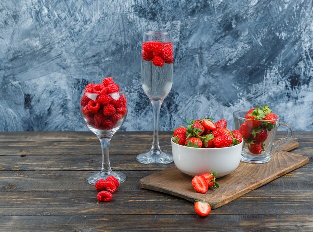 Frambuesa en vaso de cristal y fresas en un bol