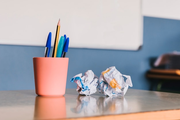 Frasco con lápices y papel arrugado.