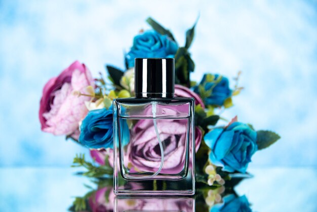 Frasco de perfume rectangular de vista frontal y flores de colores sobre fondo claro