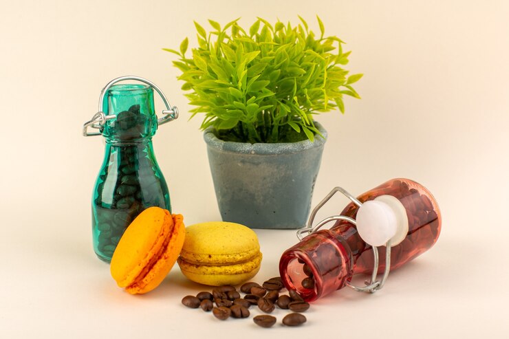 Foto gratuito un frasco de vista frontal con macarons de café francés y planta verde en la superficie rosa