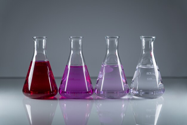 Frascos de química en una fila con líquido tóxico peligroso de diferentes colores.