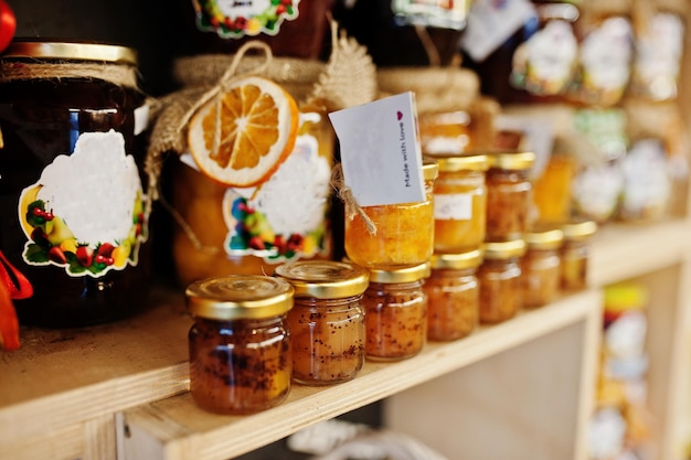 Frascos de vidrio con diferentes tipos de mermelada y bayas de los estantes de un supermercado o tienda de comestibles Productos de conservas caseras Hecho con amor