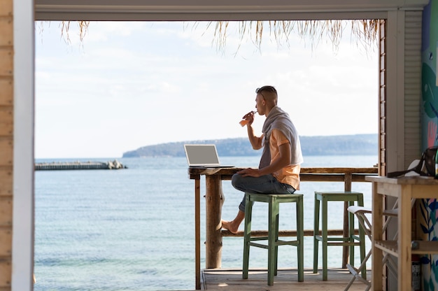 Foto gratuita freelancer de tiro completo en la playa