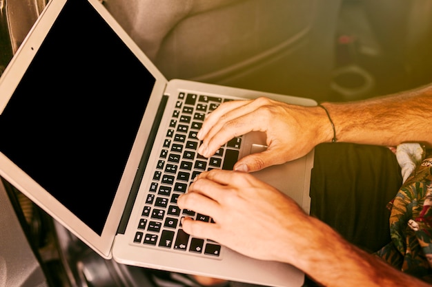 Freelancer trabajando de forma remota en la computadora portátil en el coche