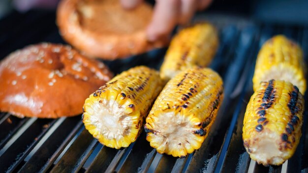 Freír mazorcas de maíz y pan de hamburguesa en una parrilla. Barbacoa