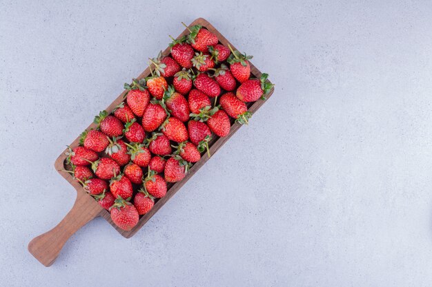 Fresas apiladas en una pequeña bandeja sobre fondo de mármol. Foto de alta calidad