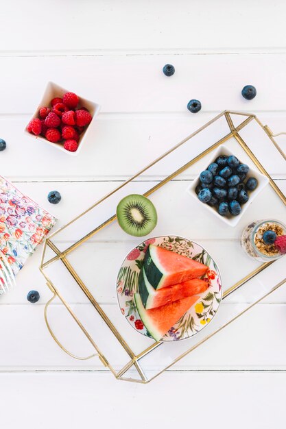 Foto gratuita fresas cerca de rodajas de sandía; kiwi; arándanos y avena en la bandeja