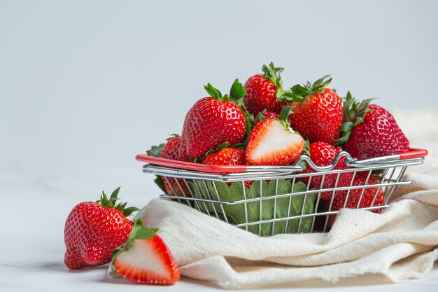 Fresas frescas en un recipiente sobre fondo blanco.