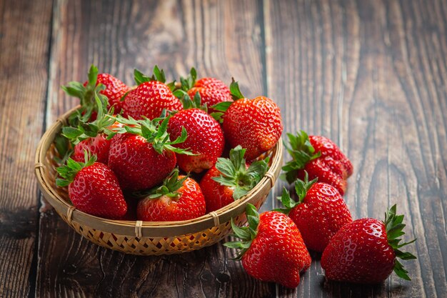 Fresas frescas en un recipiente sobre la mesa de madera