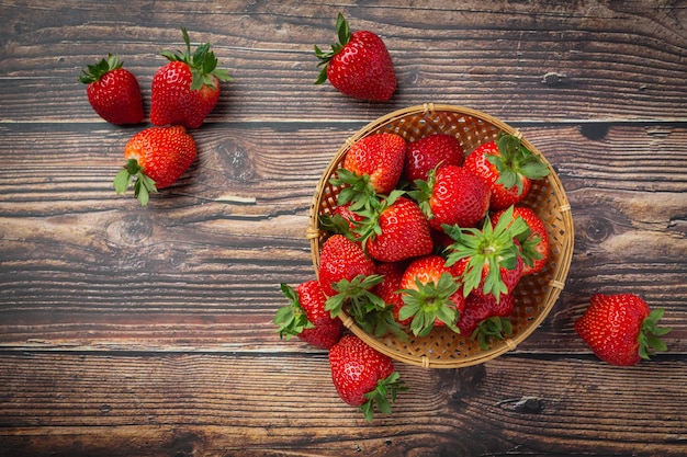 Fresas frescas en un recipiente sobre la mesa de madera