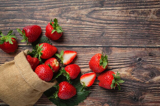 Fresas frescas en un recipiente sobre la mesa de madera