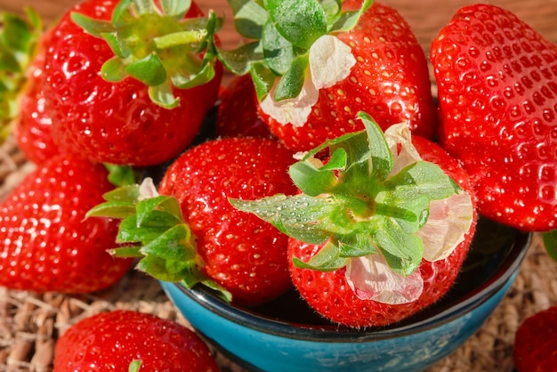 Foto gratuita fresas con gotas de agua en un tazón primer plano sobre la baya cosechada luz solar natural enfoque selectivo temporada de primavera de fresa