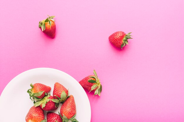 Fresas en placa sobre fondo rosa