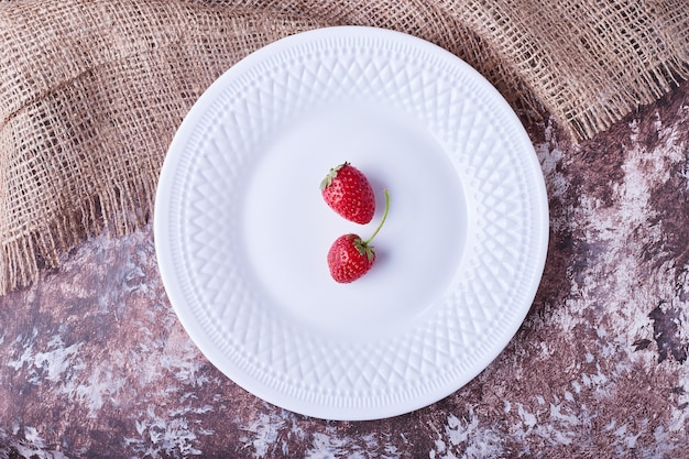 Fresas en un plato blanco, vista superior.