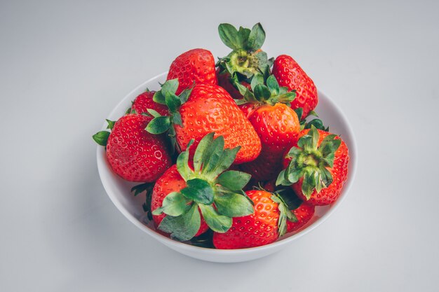 Fresas en un recipiente sobre un fondo blanco. Vista de ángulo alto.