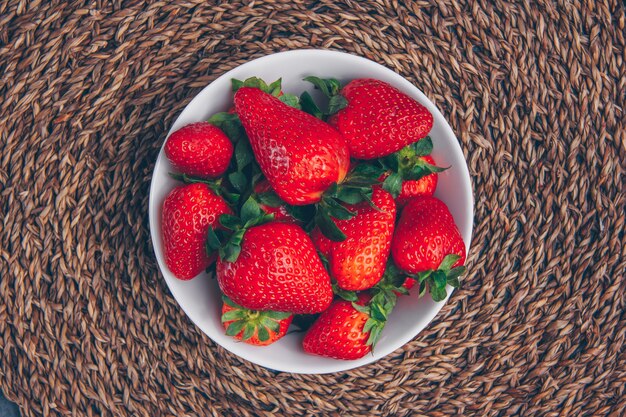 Fresas en un recipiente sobre un fondo con textura. vista superior.