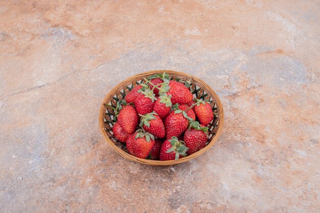 Fresas rojas en un cuenco de cerámica sobre el mármol