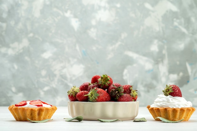 Foto gratuita fresas rojas frescas bayas suaves y deliciosas dentro de la placa con tortas en luz