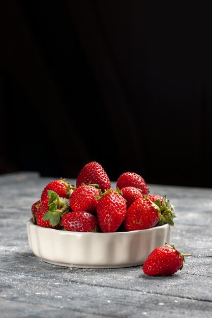 Fresas rojas frescas frutas maduras y suaves dentro de la placa en el escritorio gris