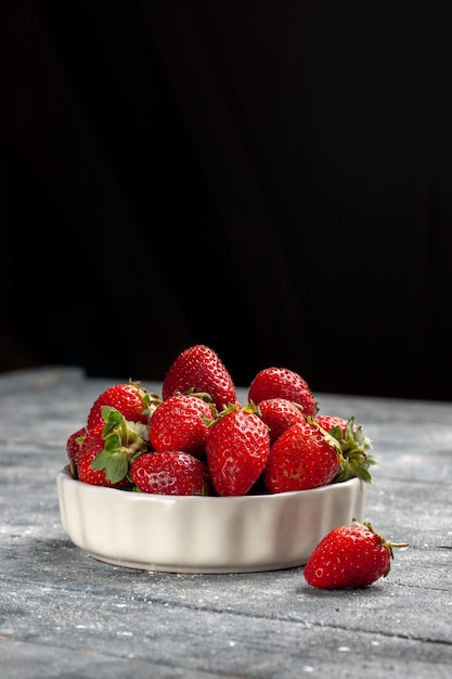 Fresas rojas frescas frutas maduras y suaves dentro de la placa en el escritorio gris