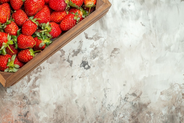 Fresas rojas frescas y naturales en una pequeña caja de madera marrón