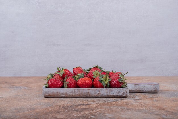 Fresas rojas en un plato rústico cuadrado.