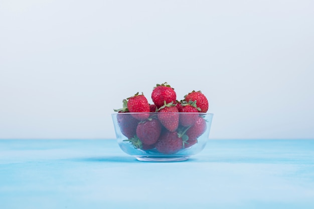 Foto gratuita fresas rojas en un vaso sobre azul en el centro.