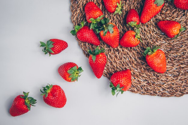 Fresas en un salvamanteles y fondo blanco. vista superior.