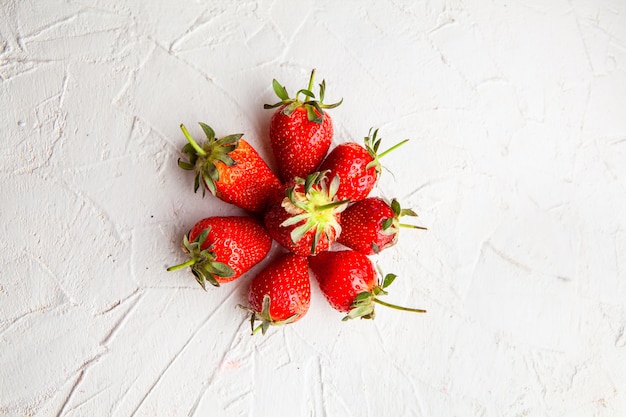 Foto gratuita fresas de la vista superior que forman el círculo en el fondo texturizado blanco. horizontal